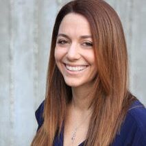 A white woman with auburn hair smiling and wearing a blue blouse.